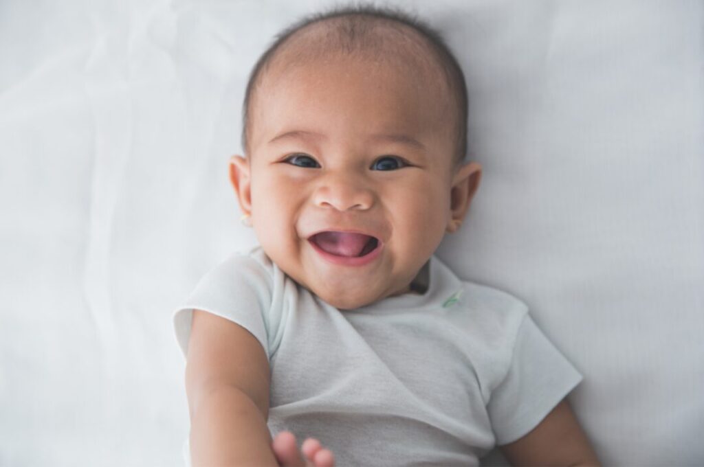 Close up image of a baby smiling with a white background.