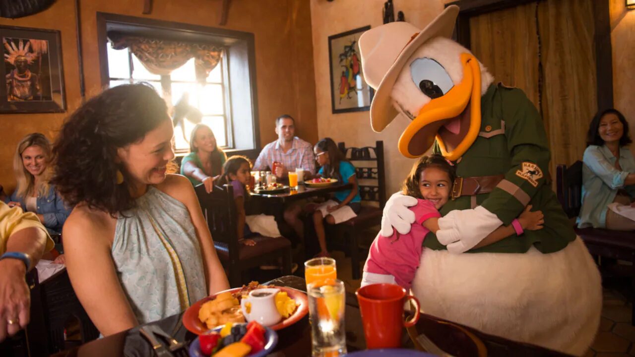 Family dining at Disney with child hugging a Disney character.